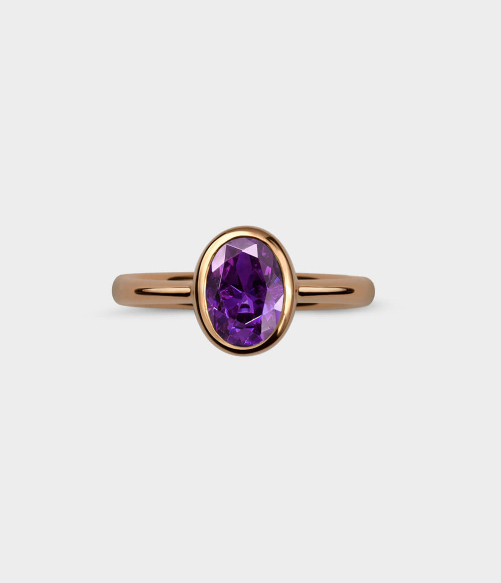 front view of an amethyst and red gold oval halo ring.